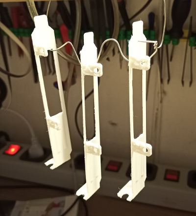 Three 3D printed slot covers hanging on a wire